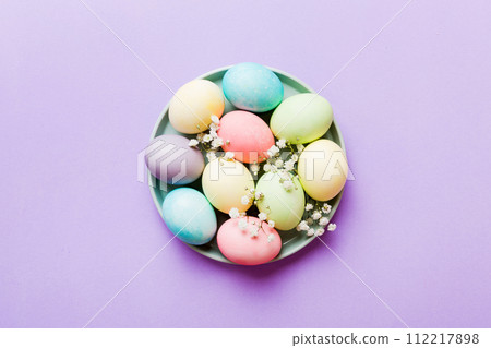 Happy Easter composition. Easter eggs in basket on colored table with gypsophila. Natural dyed colorful eggs background top view with copy space 112217898