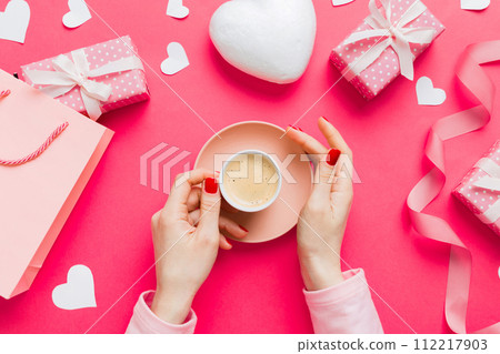 Flat lay of heart shaped cup of black coffee in the hands of women on colored background with copy space top view. Valentine day and holiday concept Flat lay of heart shaped cup of black coffee in the hands of women on colored background with copy space top view. Valentine day and holiday concept 112217903