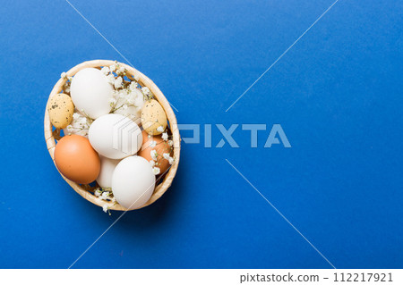 Happy Easter composition. Easter eggs in basket on colored table with gypsophila. Natural dyed colorful eggs background top view with copy space Happy Easter composition. Easter eggs in basket on colored table with gypsophila. Natural dyed colorful eggs background top view with copy space 112217921