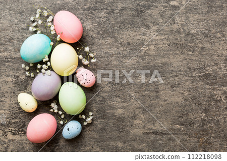 Happy Easter composition. Easter eggs on colored table with gypsophila. Natural dyed colorful eggs background top view with copy space 112218098