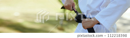 Web banner with taekwondo athlete tying black belt Web banner with taekwondo athlete tying black belt 112218398
