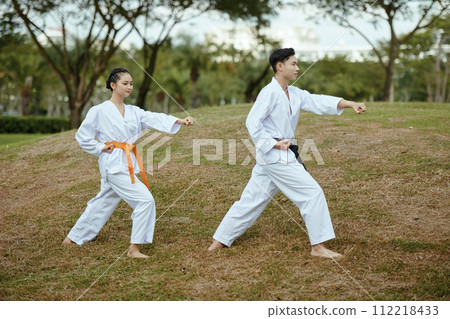 Taekwondo sportsmen in uniform working out outdoors Taekwondo sportsmen in uniform working out outdoors 112218433
