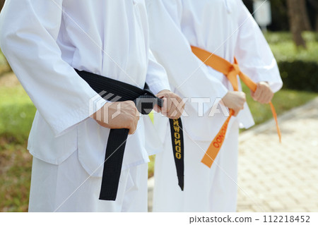 Cropped image of taekwondo athletes wearing dobok and black and orange belts Cropped image of taekwondo athletes wearing dobok and black and orange belts 112218452