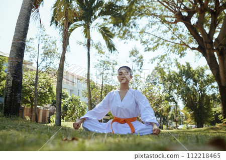 Female taekwondo athlete concentrating on breathing when meditating Female taekwondo athlete concentrating on breathing when meditating 112218465