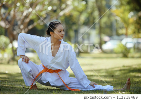 Female taekwondo athlete stretching and working out outdoors Female taekwondo athlete stretching and working out outdoors 112218469