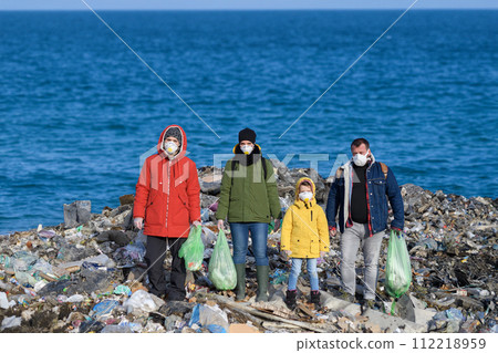 Little girl among eco activists standing on coastline, shore of sea. Environmental pollution, eco activism and plogging concept. Little girl among eco activists standing on coastline, shore of sea. Environmental pollution, eco activism and plogging concept. 112218959