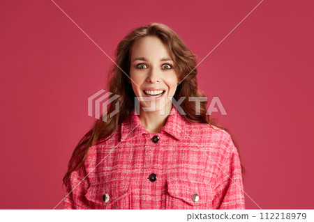 Happy and excited young woman in stylish bright clothes posing, smiling against pink studio background. Surprise, sales 112218979