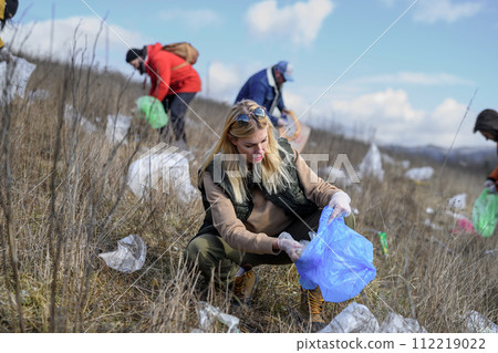 Group of activists picking up litter in nature, environmental pollution, eco activism. and plogging concept. Group of activists picking up litter in nature, environmental pollution, eco activism. and plogging concept. 112219022