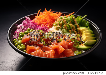 Salmon poke bowl with salmon, avocado, sesame seeds and vegetables on black table 112219734