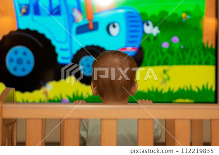 Cartoons. The kid stared at the big TV screen. Concept of knowledge of the world Cartoons. The kid stared at the big TV screen. Concept of knowledge of the world 112219835