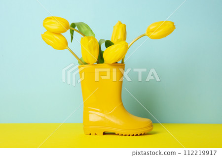 Yellow rubber boot with flowers on blue background 112219917