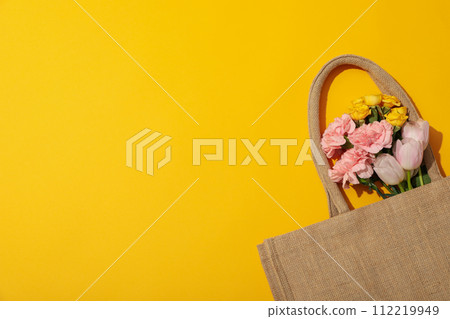 Flowers in bag on yellow background, space for text Flowers in bag on yellow background, space for text 112219949