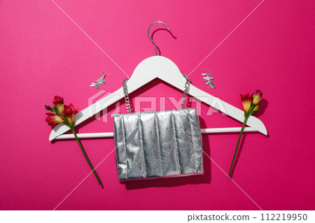 Female accessories, hanger and flowers on pink background, top view Female accessories, hanger and flowers on pink background, top view 112219950