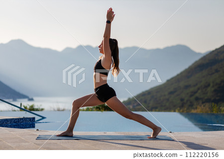 Outdoor yoga practicing at mountain resort near the pool. 112220156