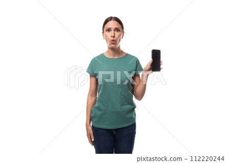 well-groomed young brunette woman dressed in a green t-shirt and jeans shows the smartphone screen 112220244