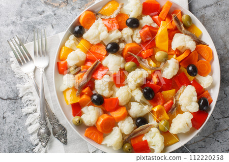 Festive Italian cauliflower salad with giardiniera, olives and anchovies close-up on a plate. Horizontal top view 112220258
