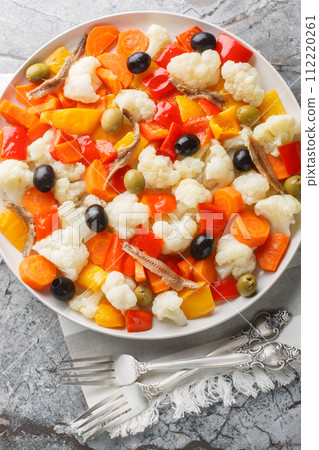 Insalata Di Rinforzo Italian cauliflower salad with giardiniera, olives and anchovies closeup on the plate. Vertical top view 112220261