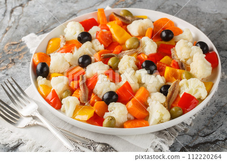 Festive Italian cauliflower salad with giardiniera, olives and anchovies close-up on a plate. Horizontal 112220264