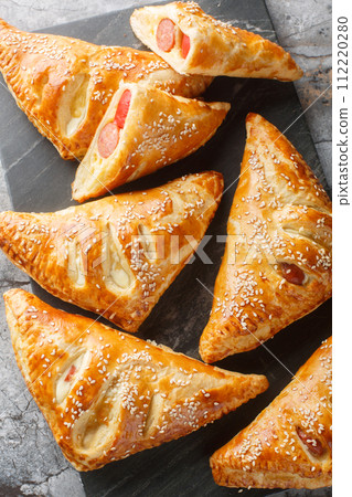 Sausage And Puff Pastry Turnovers closeup on the marble board. Vertical top view 112220280
