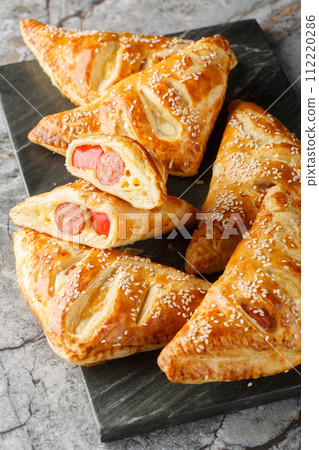 Pigs in blankets Sausage, cheese and peppers in puff pastry closeup on the marble board. Vertical 112220286