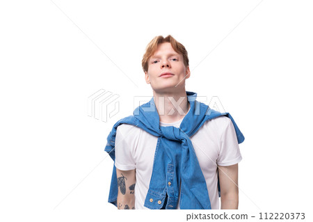 portrait of a young stylish fashionable european man with red hair and a tattoo on his arms on a 112220373
