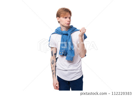 young charming slender red-haired man with a short haircut with a tattoo on his arms is dressed in a young charming slender red-haired man with a short haircut with a tattoo on his arms is dressed in a 112220383