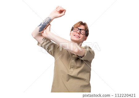 young positive red-haired european man dressed in a light brown shirt with a tattoo on his arm young positive red-haired european man dressed in a light brown shirt with a tattoo on his arm 112220421