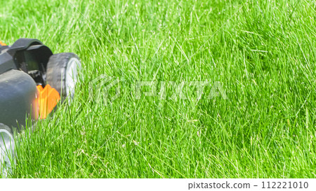 At a residential suburban house, a lush green lawn is meticulously mowed using an electric lawn mower, creating a well-manicured and inviting outdoor space. At a residential suburban house, a lush green lawn is meticulously mowed using an electric lawn mower, creating a well-manicured and inviting outdoor space. 112221010