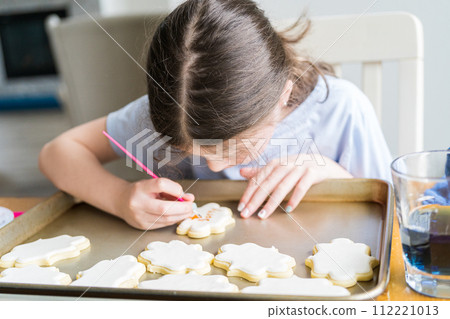 A heartwarming scene of a little girl carefully writing 'Sorry' on sugar cookies with food coloring, the cookies beautifully flooded with white royal icing. A heartwarming scene of a little girl carefully writing 'Sorry' on sugar cookies with food coloring, the cookies beautifully flooded with white royal icing. 112221013