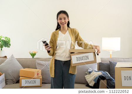 Donation concept. Woman asian holding a donate box with full of clothes. Woman holding clothes donate box. Clothes in box for concept donation and reuse recycle 112222052