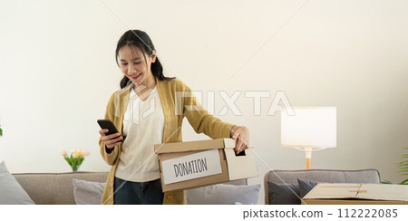 Donation concept. Woman asian holding a donate box with full of clothes. Woman holding clothes donate box. Clothes in box for concept donation and reuse recycle 112222085