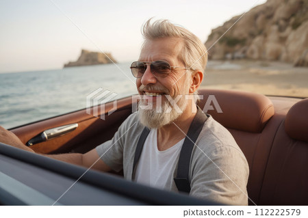 elderly man with gray beard is happy and enjoys ride in convertible car along coast sea. active and happy old age. active seniors elderly man with gray beard is happy and enjoys ride in convertible car along coast sea. active and happy old age. active seniors 112222579