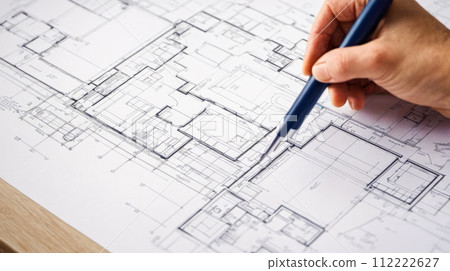 Home Remodeling Blueprint Review. Professional reviewing and making changes to detailed architectural plan for home remodeling, focusing on layout adjustments and design improvements Home Remodeling Blueprint Review. Professional reviewing and making changes to detailed architectural plan for home remodeling, focusing on layout adjustments and design improvements 112222627