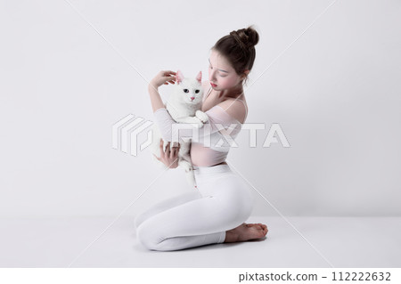 Connected to animal, bonding with pet friends. tender young girl in white clothes holding white cat against white studio background 112222632