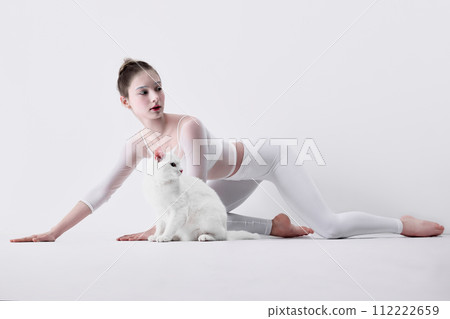 Tenderness and bonding with nature. Elegant young girl in white clothes cooperating with cute white cat against white studio background Tenderness and bonding with nature. Elegant young girl in white clothes cooperating with cute white cat against white studio background 112222659