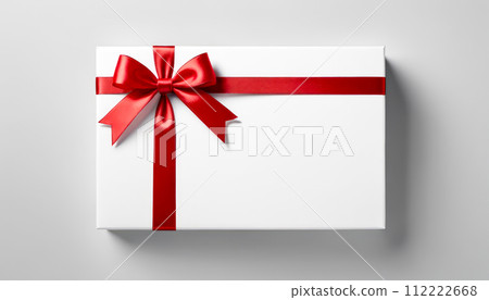Top view of neatly wrapped gift box with glossy red bow. Contrast between white box and red ribbon highlights elegance and festivity, making it suitable for holiday themes and special events 112222668
