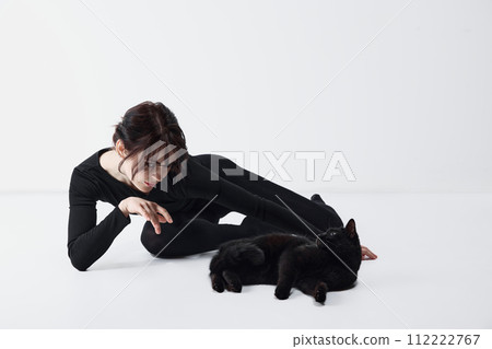 Bond between human and pet. Beautiful young woman in black clothes playing with black cat against white studio background Bond between human and pet. Beautiful young woman in black clothes playing with black cat against white studio background 112222767