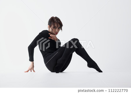 Inner fears. Emotive young woman in black clothes, with dark eyes makeup sitting on floor with emotive face against white studio background Inner fears. Emotive young woman in black clothes, with dark eyes makeup sitting on floor with emotive face against white studio background 112222770