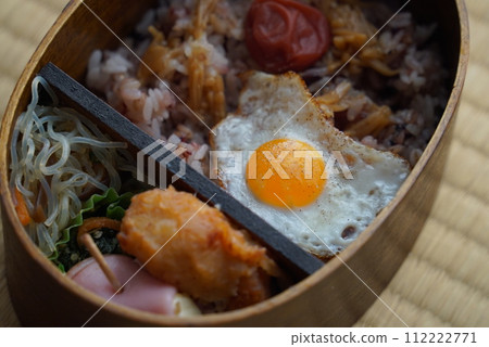 Japanese-style bento with fried egg and pickled plums in a wooden bento box Japanese-style bento with fried egg and pickled plums in a wooden bento box 112222771