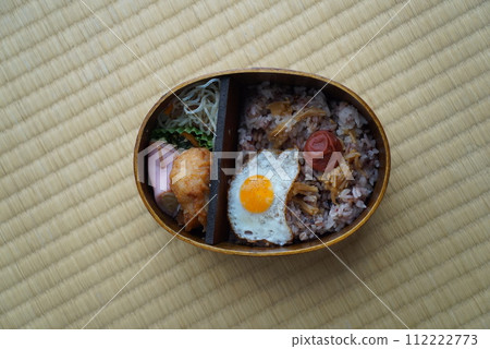 Japanese-style bento with fried egg and pickled plums in a wooden bento box Japanese-style bento with fried egg and pickled plums in a wooden bento box 112222773