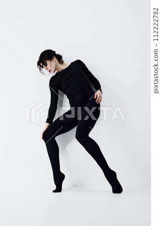 Full-length image of passionate, artistic young woman with smoky eyes makeup, black clothes standing in dynamic pose against white studio background 112222782