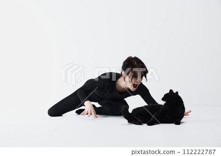 Artistic beautiful woman in emotional stance with black cat, both displaying dynamic expressions of anger, shouting against white studio background. Artistic beautiful woman in emotional stance with black cat, both displaying dynamic expressions of anger, shouting against white studio background. 112222787