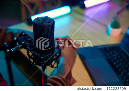 Focus on female hands, microphone and laptop. Blogger making online podcast show, discussing interesting lifestyle topics Focus on female hands, microphone and laptop. Blogger making online podcast show, discussing interesting lifestyle topics 112222809