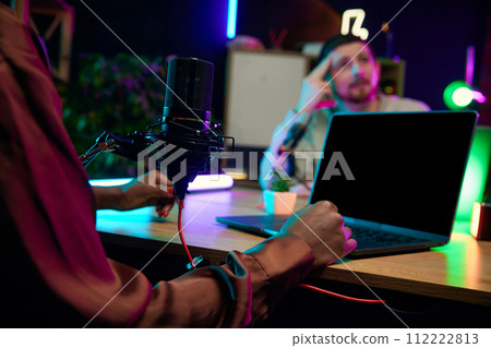 Focus on female hands, microphone and laptop. Blogger making online podcast show, discussing interesting lifestyle topics Focus on female hands, microphone and laptop. Blogger making online podcast show, discussing interesting lifestyle topics 112222813