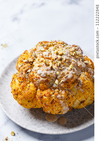 Spicy baked cauliflower with tahini dressing and pistachios. 112222848