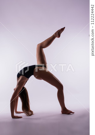 Young beautiful female yoga posing on a gray studio background 112224442