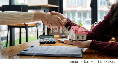 Estate agent and customer shaking hands after finished contract after about home insurance and investment loan Estate agent and customer shaking hands after finished contract after about home insurance and investment loan 112224689