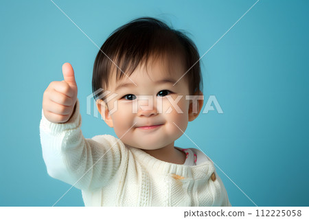 Cheerful  Toddler Giving Thumbs Up on Solid colored Background 112225058