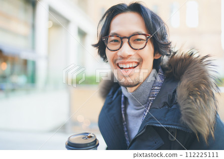 A man wearing a coat walking with coffee in hand A man wearing a coat walking with coffee in hand 112225111