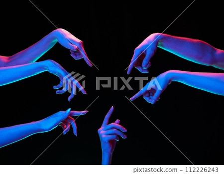 Hands in multicolored neon lighting with pointing gesture against black studio background. Opinion, self-expression. 112226243